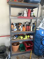 Front view of metal shelving unit showing four OSB particleboard shelves with various garage items on them.