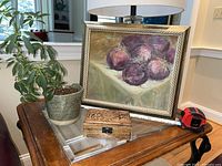 Photo showing the full setup on a table with the painting, planter with plant, and wooden box together.