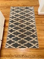 Full view of the rectangular Ruggable area rug with blue geometric patterns on cream background, lying on hardwood flooring.