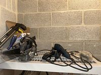 Craftsman sander and Ryobi multi-tool on a white shelf in a basement wall
