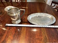 Silver-plate hammered pitcher and pewter serving tray together with a measuring tape showing size.