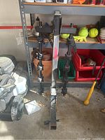 Full view of the Thule bike rack including arms with securing straps hanging from a shelf in a garage, showing its size and design.