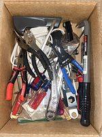 Overhead view of the box showing a variety of hand tools including pliers, screwdrivers, wrenches, wire strippers, and a pry bar hammer in the box.