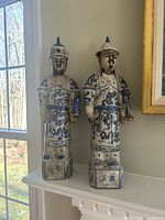 Front view of two ceramic Asian-styled figurines showing detailed painted dragon designs and traditional clothing.