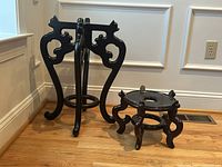 Two Asian inspired dark wood plant stands shown side by side on floor, no pots or plants included.