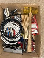 Top down view of open box showing wooden handled rubber mallet, cables, screwdrivers, shank pins pack, and assorted hand tools underneath