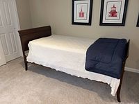 Side view of bed frame with white quilt and blue comforter
