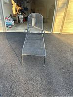 Front view of black wrought iron mesh chaise lounge.