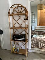 Full view of the 4-tier bamboo shelf showing the natural bamboo frame, decorative design, and four shelves with various items present.