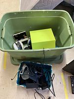 Photo showing two storage bins: one containing a Nintendo DS handheld console, game cartridges, and Beats headphones; the other containing Xbox accessories including cables and power adapters.