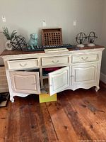 Front view of buffet cabinet showing three drawers, three doors, decorative apron and distressed finish