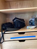 Two black camera gear bags and a box of Polaroid film on a wooden shelf