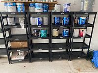 Front view of 5 black Nexus plastic display shelves with various paint cans and boxes on shelves (items not included)