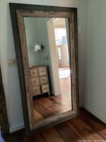 Full view of mirror leaning against wall showing complete frame and reflection