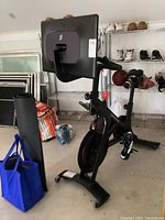 Full view of Peloton Bike+ with touchscreen, flywheel and attached cycling shoes