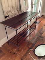 Full view showing the table's metal base with parallel rods on the bottom shelf and three dark stained wood slats on top.