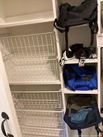 Overall view of shelving unit with backpacks, ski goggles, gloves, and outerwear items