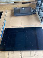 Samsung flat screen TV and Sunbrite outdoor TV placed on cardboard with a garage background, showing full front views of screens.