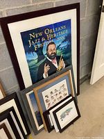 Large framed New Orleans Jazz & Heritage Festival 2000 poster leaning against cinderblock wall