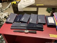 Overview of wristwatch, multiple branded pouches and case backs on red table