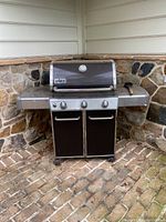 Front view of the Weber Genesis gas grill with two black cabinet doors and four knobs.