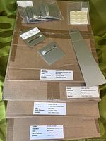 Aluminum panels stacked with some mounting hardware on top showing part labels