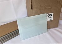 Photo showing frosted beveled glass panel leaning against cardboard box with packaging materials visible.