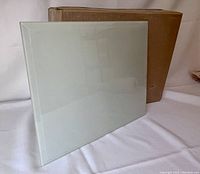 Front view of one frosted, bevelled glass panel propped against a cardboard box on white fabric backdrop.