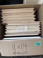 Cardboard box holding multiple 11x14 bevelled natural pine plaques stacked vertically.
