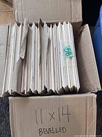 Box containing multiple bevelled natural pine plaques, stacked vertically, marked 11 x 14 bevelled.