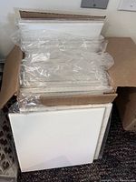 Open box showing multiple stacked 8 x 8 inch white glossy tiles, some still wrapped in plastic.