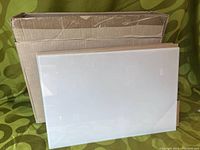 Single frosted glass panel leaning against packaging box on patterned fabric background.