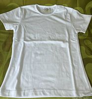 Photo of single white ladies small fit t-shirt laid flat showing front side, confirming condition and style.