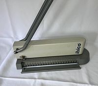 Front angle view showing the white body and gray base, metal dual levers, and Ibico label on the side.