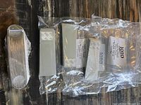 Plastic wrapped metal bottle openers and table top easels on a wooden surface.