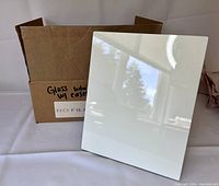 Gloss white photo panel front showing reflective glossy finish and cardboard box in background