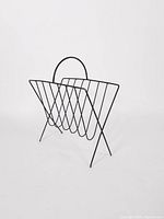 Side view of vintage black metal holder showing zigzag wire slots and curved handle