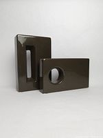 Two brown ceramic vases, one tall with a rectangular cutout and one shorter with a circular cutout, shown from a front angle.