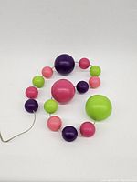 Image showing full length of colorful spherical LED lamp balls, strung in a linear arrangement on clear wire.