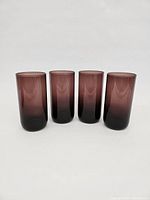 Front view of the set of four Libbey amethyst purple tall glasses, showing their shape, color, and finish.