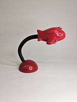 Front side view of the red ceramic airplane lamp with flexible black neck and red dome base, showing the airplane motif in full profile.