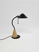 Side view of the desk lamp showing curved neck and wooden cone base on circular black metal platform.