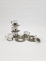 All espresso cups stacked and one cup tipped over showing the inside of the cup and chip damage on one cup under its base.