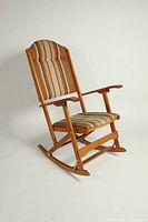 Front view of the vintage wooden rocking chair with striped upholstery, showing the full chair with armrests and a curved top backrest.