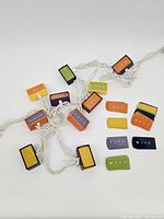 Overall view of 10 multicolored word box lights connected by white wiring forming the hanging lamp.