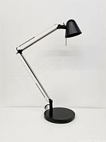 Full view of Ikea Uppbo desk lamp showing adjustable arm, black conical lamp head, and round base.