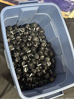 Plastic bin filled with numerous black caster wheels measuring approximately 2.36 inches each.