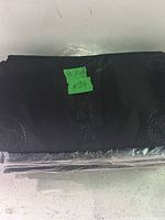 Photo of black folded fabric pieces stacked, showing texture and circular patterns