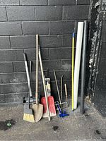 Photo showing the 13 construction hand tools against a black brick wall for size and condition verification.