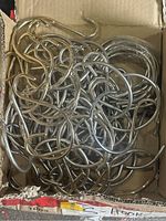 Box containing over 50 silver metal S-hooks, showing quantity and general condition.